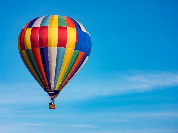 panning photography of flying blue, yellow, and red hot air balloon